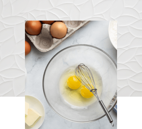 Bowl with egg whites and yolks with whisk