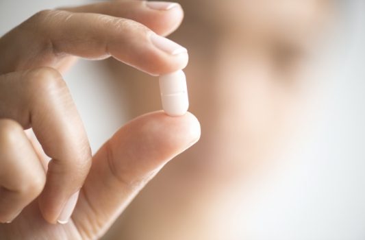 Person holding a white pill for oral sedation dentistry in Lorain