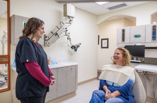 Dental team member chatting with a patient in the dental chair